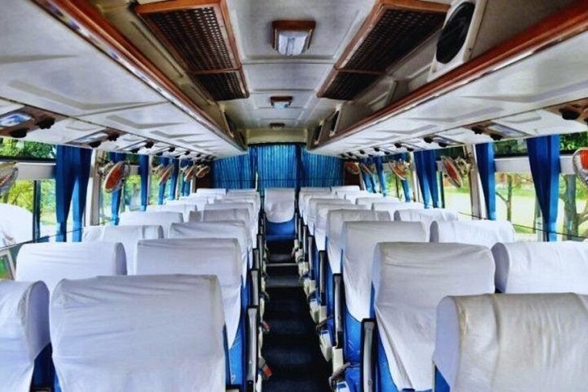 A train interior with rows of white seats, blue curtains, and overhead luggage racks. 2