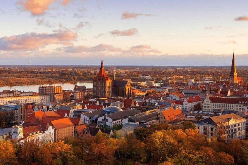 A cityscape with prominent church spires, a river, and autumn foliage. 4