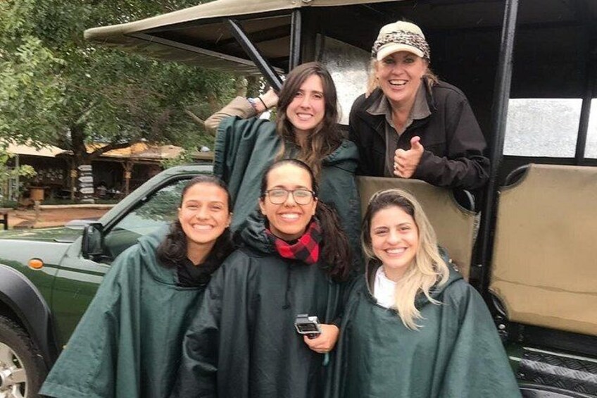 A group of people in green rain ponchos standing in front of a vehicle. 2