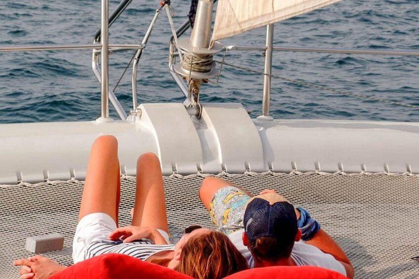 Una persona acostada sobre la cubierta de un barco con una vela, usando sombrero y camisa a rayas. 4