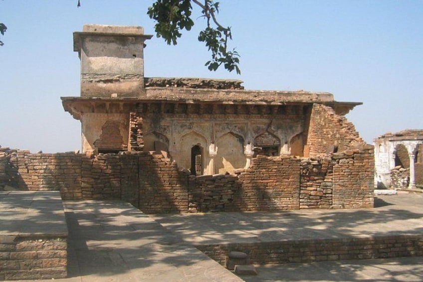 An ancient brick structure with arched doorways and a chimney. 2