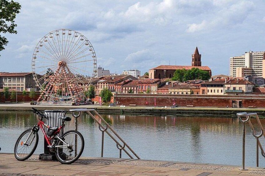 Et pariserhjul, en cykel, en flod og historiske bygninger. 4