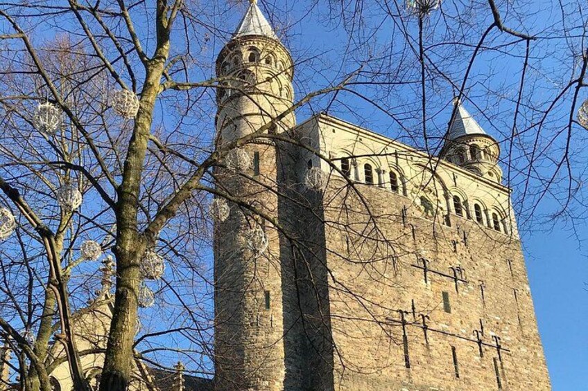 A historic tower with arched windows and a pointed roof, surrounded by leafless trees. 1