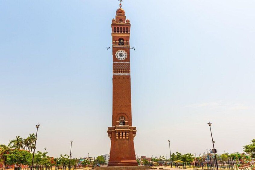 A tall brick tower with a clock, surrounded by palm trees and street lamps. 3
