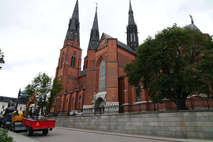 A red brick church with three spires and a statue on top. 3