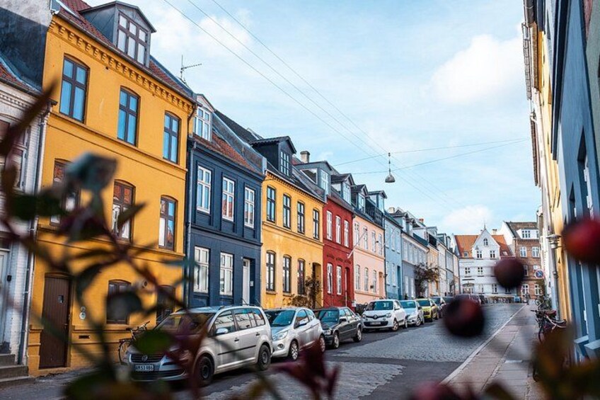 A street lined with colorful buildings, parked cars, and a bicycle. 3