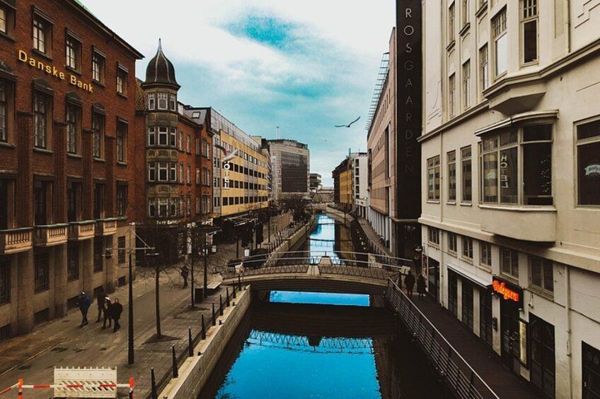 A canal with buildings on either side, a bridge, and a clear sky. 5