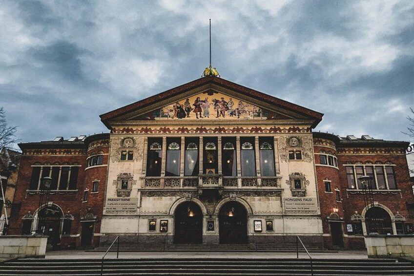A historic building with a central entrance, large windows, and decorative sculptures on the facade. 3