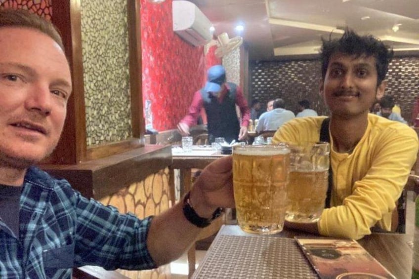Two people sitting at a table with a glass of beer each. 1
