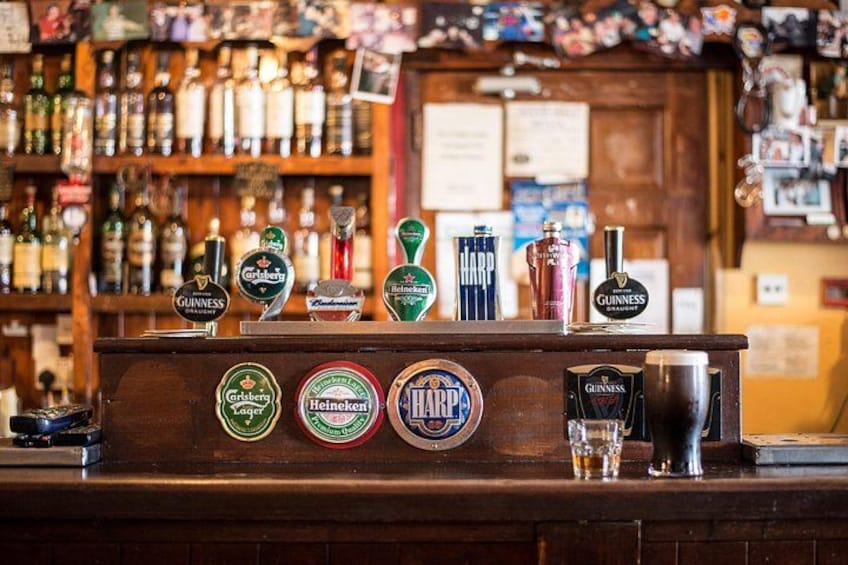 A bar counter with beer taps and a variety of bottles in the background. 3
