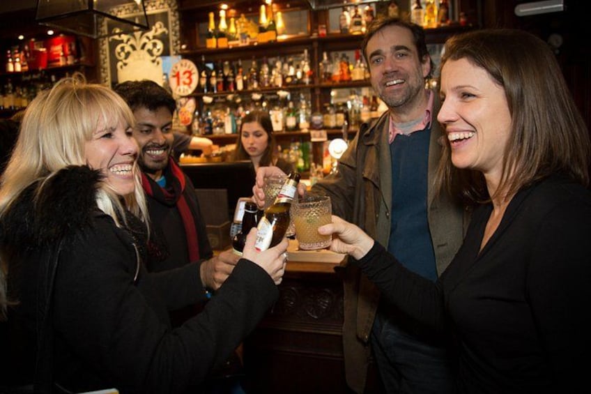 A group of people toasting with drinks in a bar. 5
