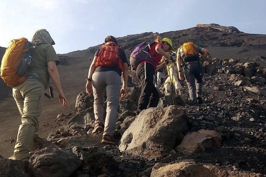 A group of hikers on a rocky trail with a mountainous background. 4