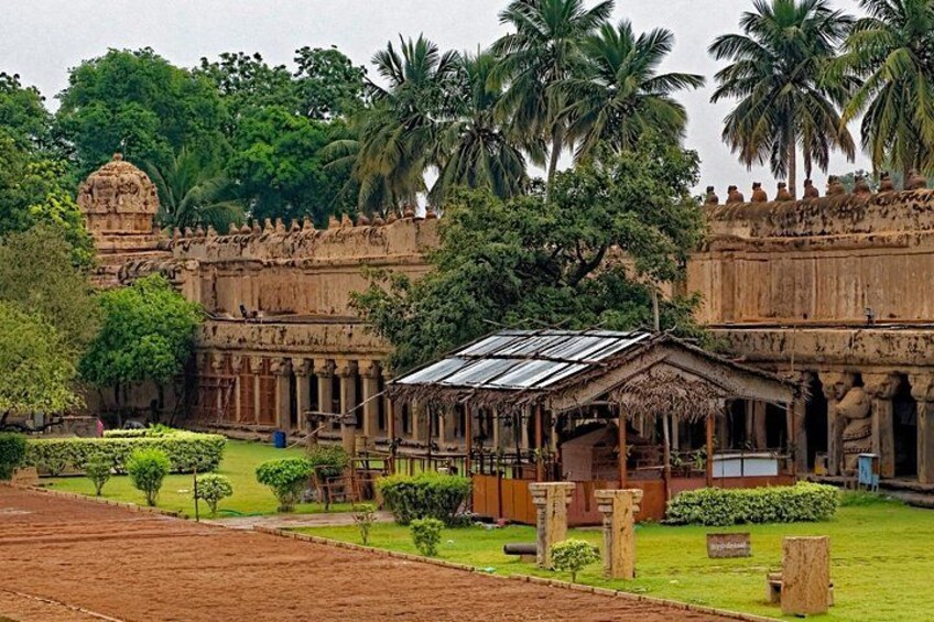 A historic temple complex with a central shrine, surrounded by lush greenery and palm trees. 2