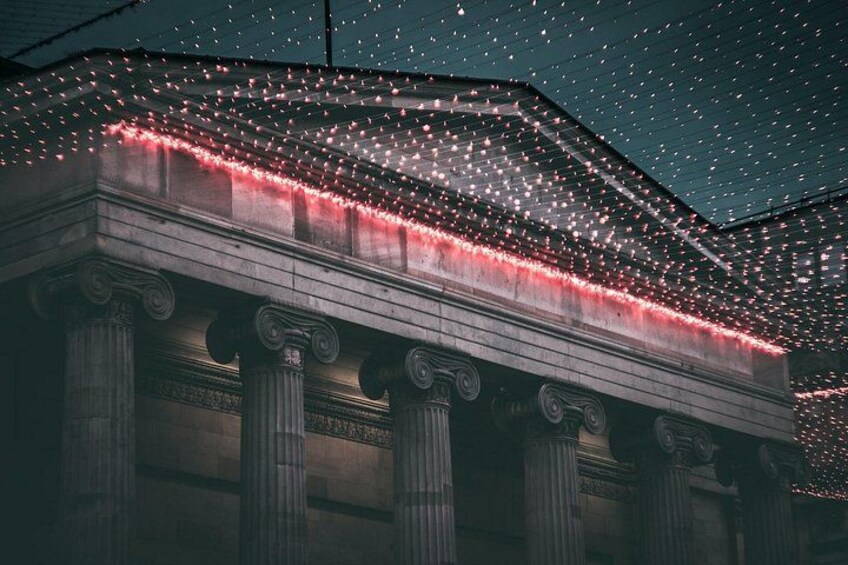 A building with classical architecture, adorned with string lights. 2