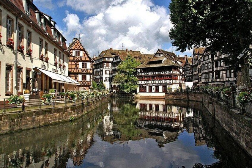 A canal with buildings reflecting on the water, a bridge, and a clear sky. 5