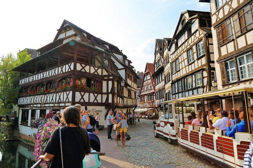 A cobblestone street with traditional half-timbered buildings, a canal, and a rowboat with passengers. 4