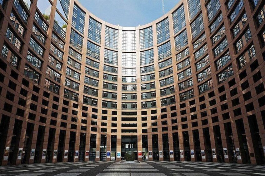 A modern curved building with a grid of windows and a central entrance. 3