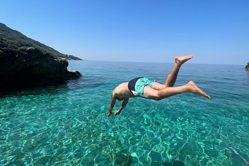 Una persona se sumerge en aguas turquesas cristalinas cerca de una costa rocosa. 2