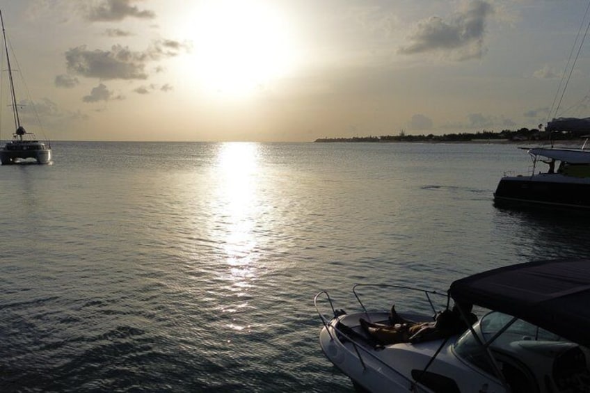 A calm sea at sunset with boats and a distant shoreline. 2