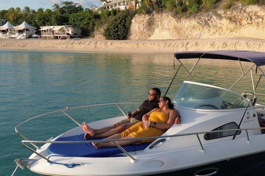 A couple relaxing on a boat with a beach and houses in the background. 3