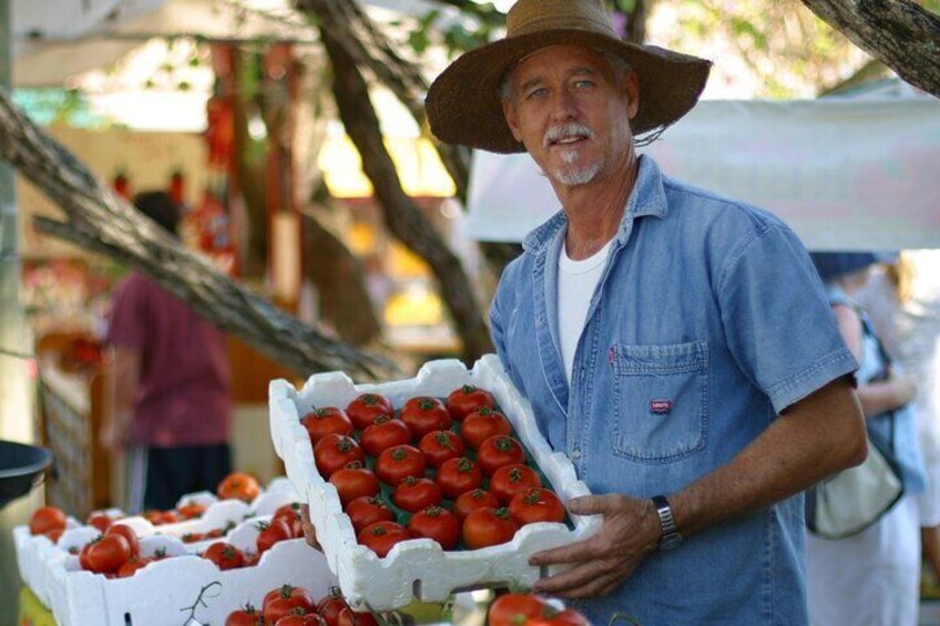 Un homme tenant une caisse de tomates dans un marché en plein air. 5