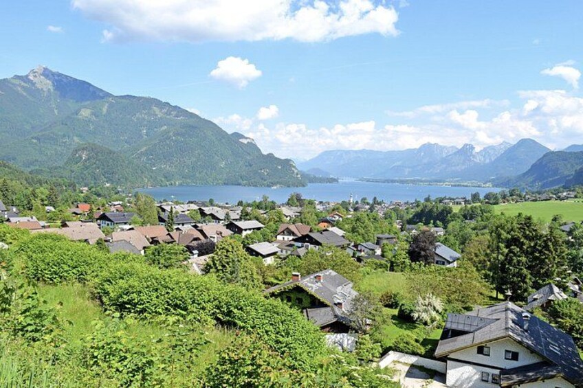 Un pueblo a orillas del lago rodeado de casas, vegetación y montañas al fondo. 5