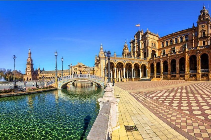 Un bâtiment historique doté d’une grande cour, d’un pont enjambant un plan d’eau et d’une allée pavée. 1
