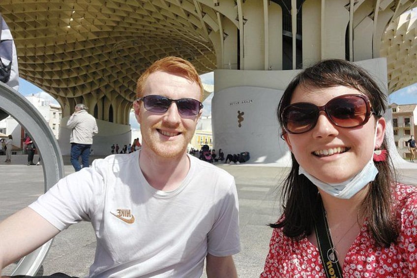 Two people taking a selfie in front of a modern architectural structure with a unique geometric design. 2