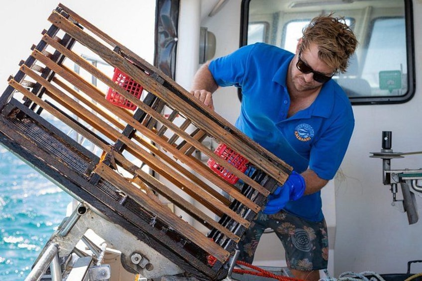 A person handling a wooden crate on a boat. 2