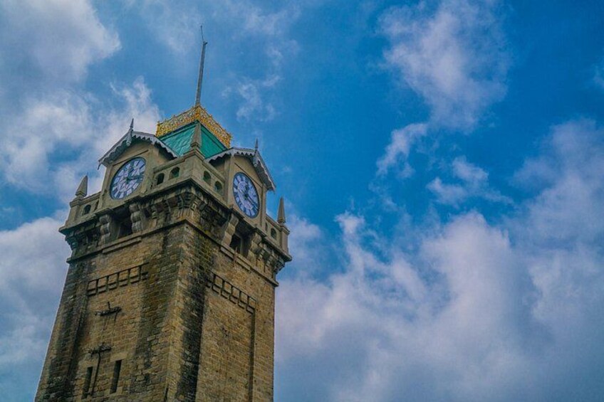 A tall clock tower with a green roof and two clocks on each side. 4