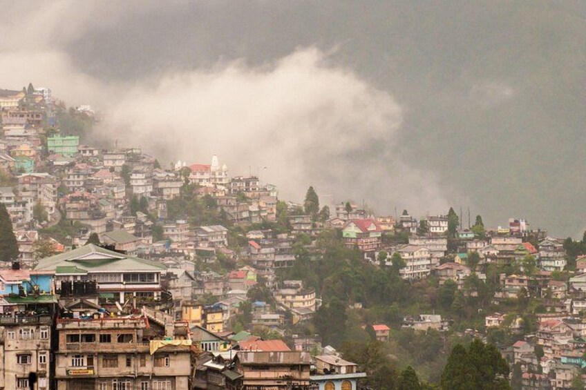 A densely populated hillside settlement with traditional architecture, under a cloudy sky. 1