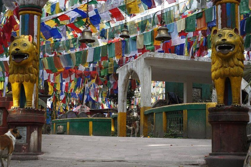 A temple with colorful prayer flags, golden lion statues, and a bell. 5