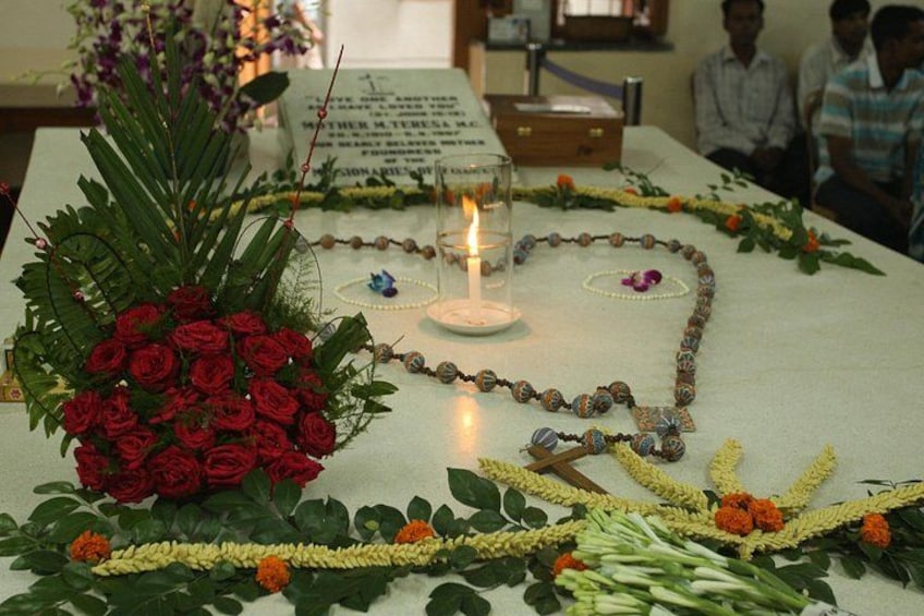 A table with a bouquet of red roses, a candle, and a garland of yellow and orange flowers. 1