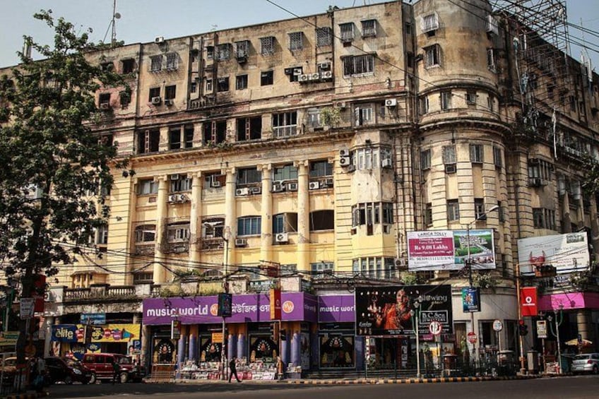 A multi-story building with commercial establishments on the ground floor, including a music store and a pharmacy. 4
