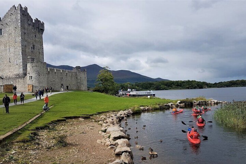 A castle, kayakers on a lake, and a grassy area with people walking. 5