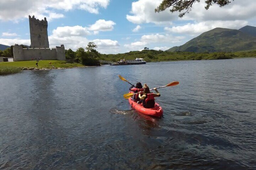 A red kayak on a calm river with a castle in the background. 1