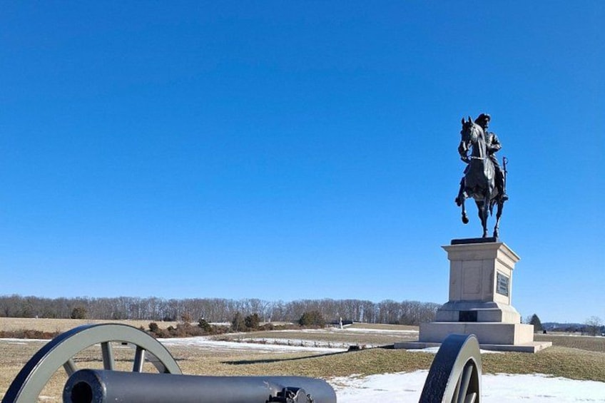 Une statue représentant une figure à cheval, placée sur un piédestal, avec un ciel bleu clair en arrière-plan. 2