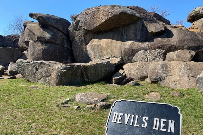 De gros blocs de pierre, une zone herbeuse et un panneau indiquant « Devil’s Den ». 5