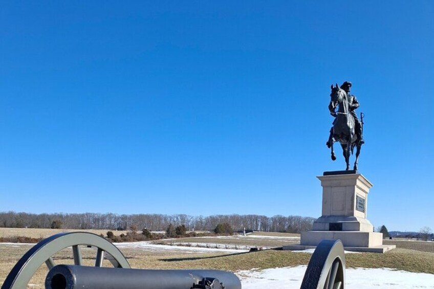 Una estatua de una figura a caballo sobre un pedestal, con un cielo azul despejado al fondo. 2