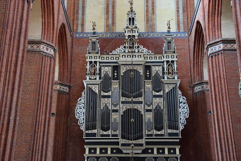 En detaljeret facade af en kirke med udsøgte, sort-hvide dekorationer, herunder en markant centraldør med indviklede udskæringer og statuer over døren. 2