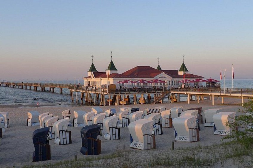 A pier with a building, beach chairs, and a view of the sea. 2