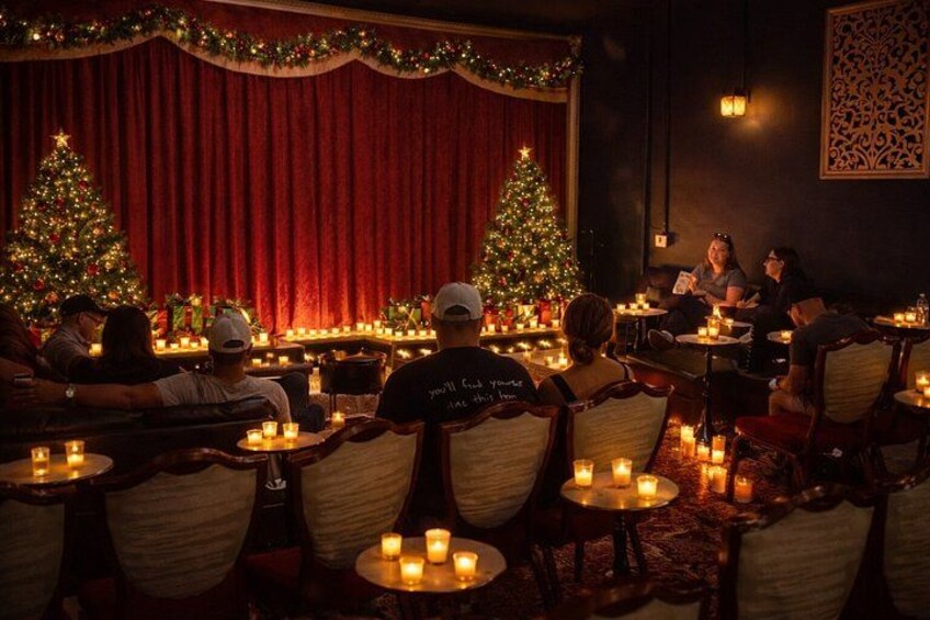 A cozy indoor setting with Christmas trees, tables with candles, and people seated. 3