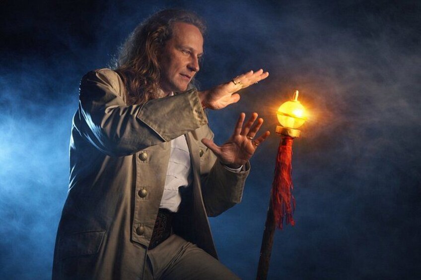 A person in a long coat with a glowing orb on a pole. 2