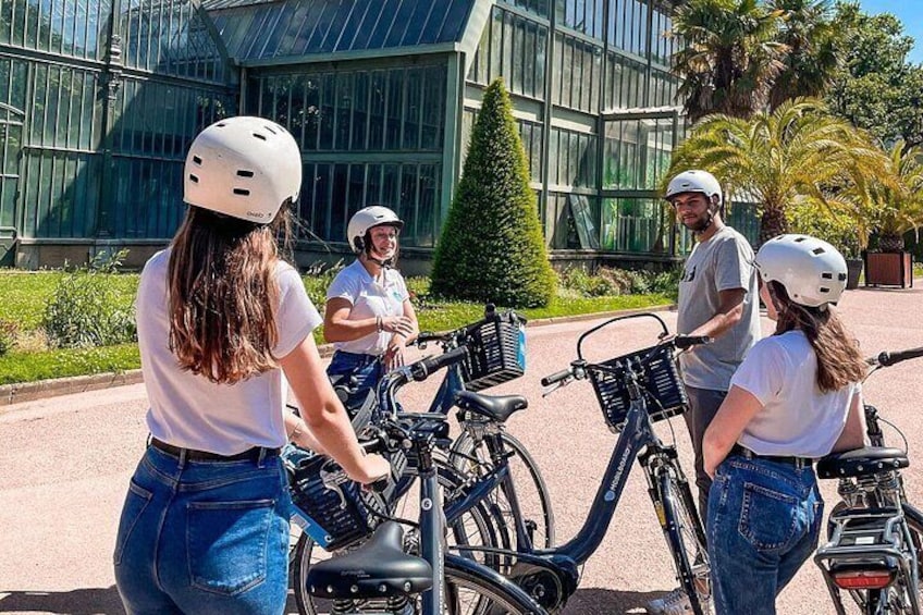 A group of people with helmets standing beside bicycles in front of a modern building with glass windows. 3
