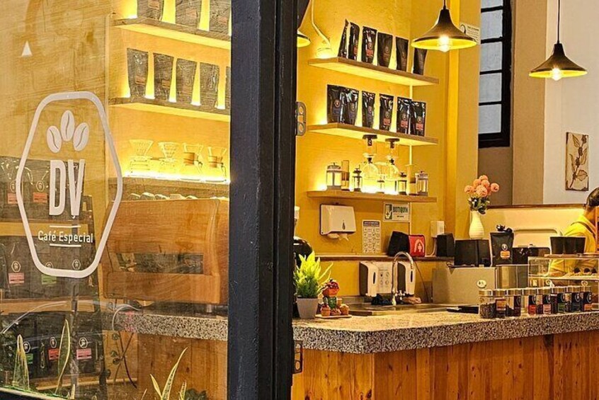 A café interior with wooden shelves, a coffee machine, and a sign reading 'DV Café Especial.' 5