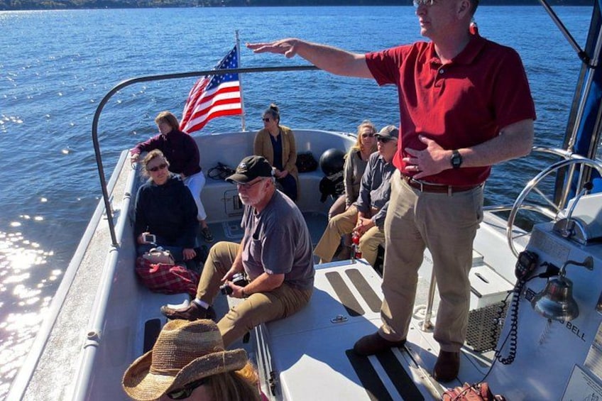 A boat with people on board, an American flag, and a person pointing towards the water. 3