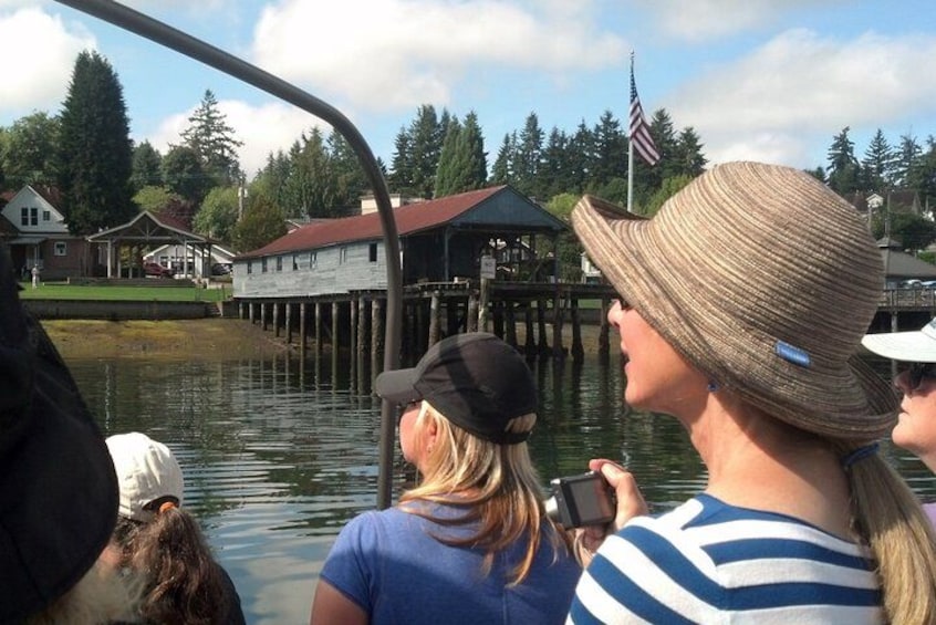 A group of people on a boat, a dock, and a house with a red roof. 2