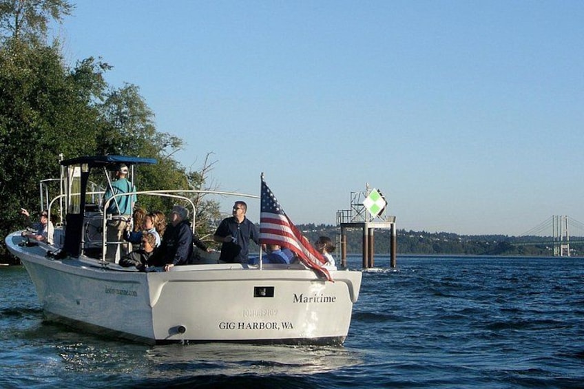 A boat named 'Maritime' with 'GIG HARBOR, WA' written on it, sailing on water with a bridge in the background. 5