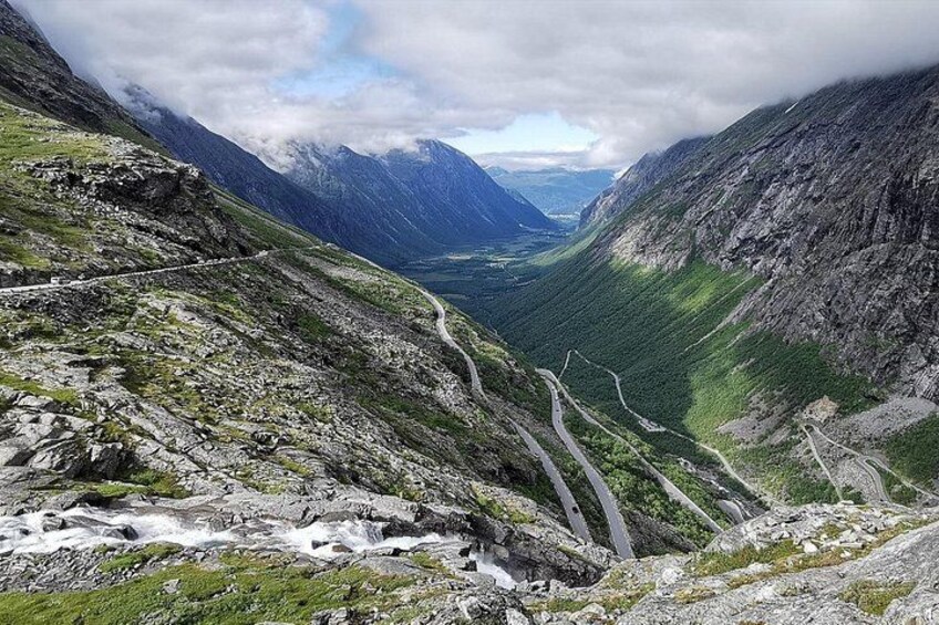 A mountain road winding through a valley with rocky terrain and greenery. 2