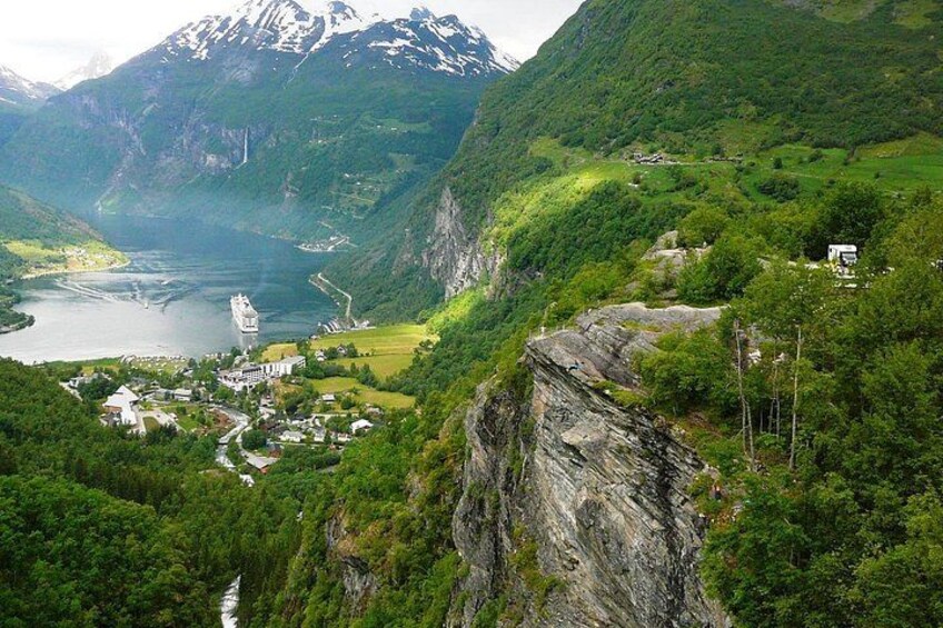 A fjord with a village, mountains, and a waterfall. 1